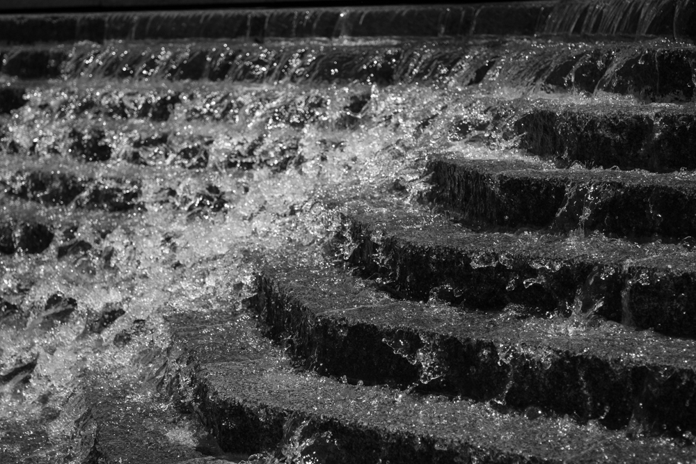 Water torrents down rock steps in a fountain.